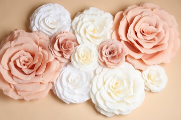Beautiful paper flowers on beige background, flat lay