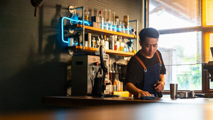 Small business entrepreneur coffee shop owner concept. Asian man cafe waiter or coffee barista using kitchen towel sweeping and cleaning counter bar and preparing equipment to get ready for opening.