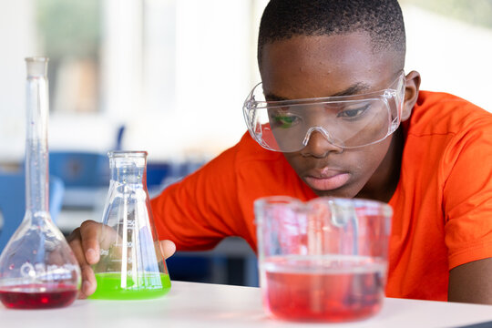 In school, boy conducting science experiment with beakers and safety goggles