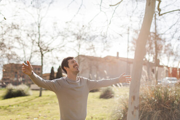 Man seen from behind with arms wide open, connecting with nature. Transmits freedom, mindfulness,...
