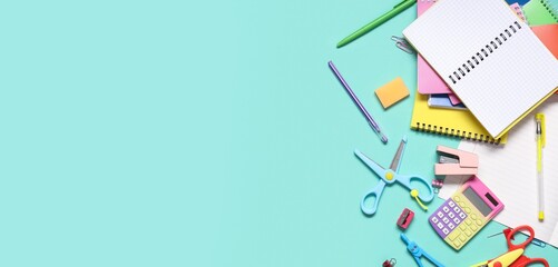 Different stationery on turquoise background with space for text