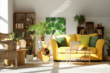 Interior of stylish living room with yellow sofa, laptop on coffee table and houseplants