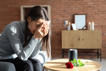 Mourning young woman crying near mortuary urn at funeral