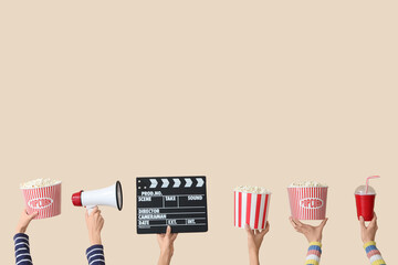 Many hands with movie clapper, buckets of popcorn and megaphone on beige background