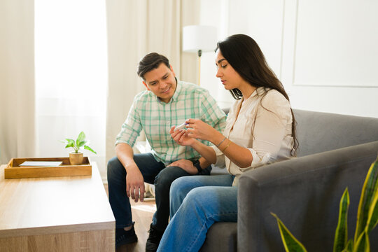 Young woman showing a medical test result to her supportive partner while sitting on the sofa at home