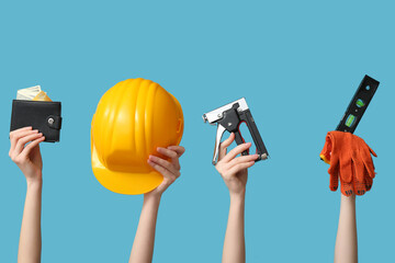 Female hands with construction tools and wallet on color background