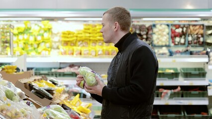 Shopper selects fresh produce from the fruit and vegetable section, examining a bag of pears while reading the label. Man choosing fruits in supermarket, shelf with apples