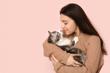 Young woman holding cute longhaired cat on pink background © Pixel-Shot
