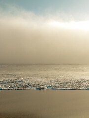 Low angle view of a sandy beach with marine layer clouds hovering above the horizon at sunset