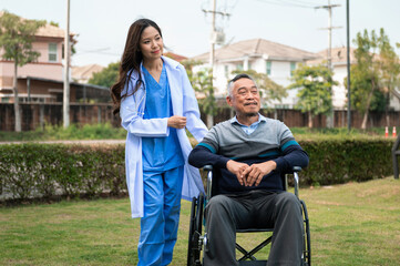 A woman in a blue scrubs is helping an elderly man in a wheelchair