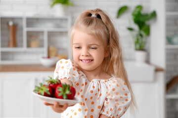 Little girl holding plate of strawberries in kitchen