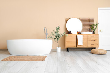 Interior of light bathroom with bathtub, ceramic sink and chest of drawers