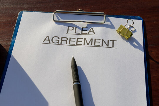 Legal document titled &ldquo;Plea Agreement&rdquo; placed neatly on a clipboard set on the desk with pen, representing justice and legal process.