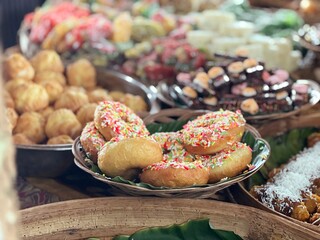 A variety of delicious and colorful traditional Indonesian market snacks, with the main focus being donuts sprinkled with colorful chocolate sprinkles.