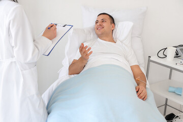Obraz premium Male patient on bed talking to doctor in hospital ward
