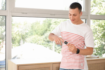 Young man with pulse oximeter at home