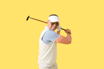 Mature man playing golf on yellow background