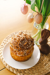 Beautifully decorated Easter cake topped with icing and chocolate sprinkles sits alongside a chocolate bunny and pastel eggs. The cheerful arrangement radiates holiday joy.
