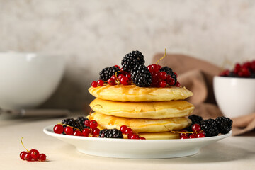Plate of sweet pancakes with fresh blackberries and red currants on white background