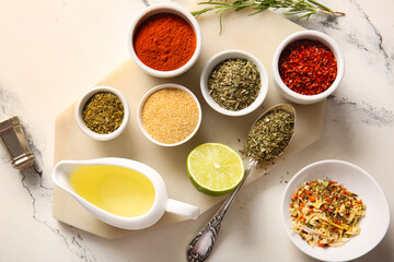 Board with different spices and oil on light background
