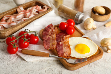 Board with fired egg, bacon, tomatoes, mushrooms and jars of spices on white background