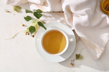 Cup of linden tea with leaves and napkin on white background