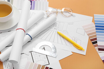 Architect's supplies with house plans and tea cup on orange background, closeup
