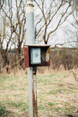 A rusted metal box with a metal pole