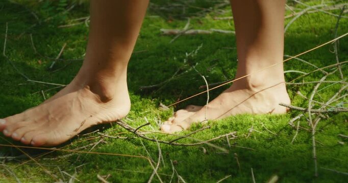 Bare feet walking on soft green moss in a quiet forest