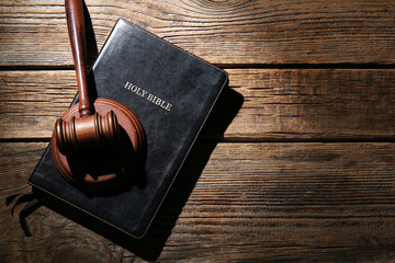 Holy Bible with judge's gavel on dark wooden background