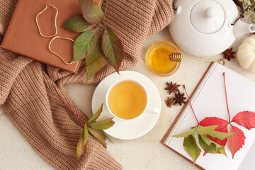 Composition with notebooks, cup of green tea, tea pot and sweater on light grunge background