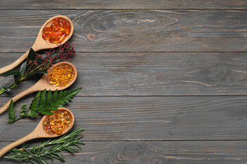 Spoons with different pills and herbs on wooden background