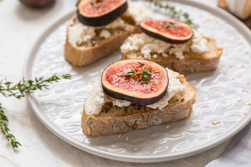 Plate of delicious fig bruschetta with ricotta cheese on white background, closeup