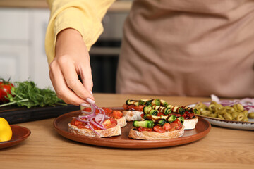 Woman cooking vegan bruschettas at table in kitchen, closeup