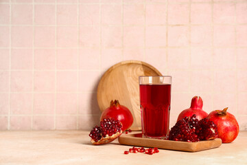 Glass of fresh pomegranate juice and fruits on beige table