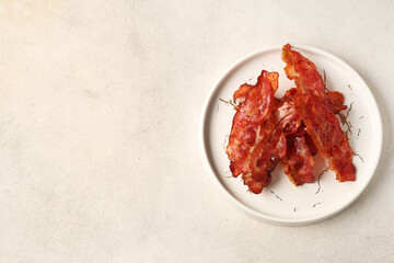 Plate with fried bacon rashers on white background