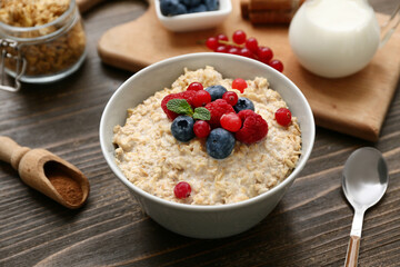 Composition with tasty oatmeal and berries on wooden background