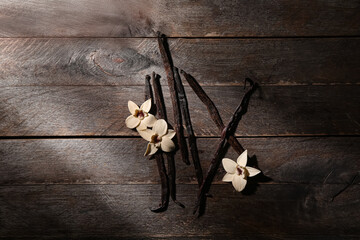 Aromatic vanilla sticks and flowers on dark wooden background
