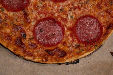 a salami pizza on baking paper
