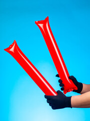 Close-up of red inflatable cheering sticks for bright and loud support of teams on blue background