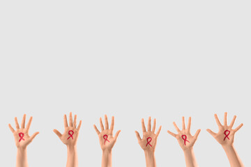 Female hands with drawn red ribbons on light background. Blood cancer awareness concept