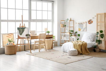 Interior of teenager's room with bed, workplace and easel