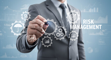 Man in Gray Suit Writing Risk Management Concept Overlaid on Gears and Business Icons on Blue