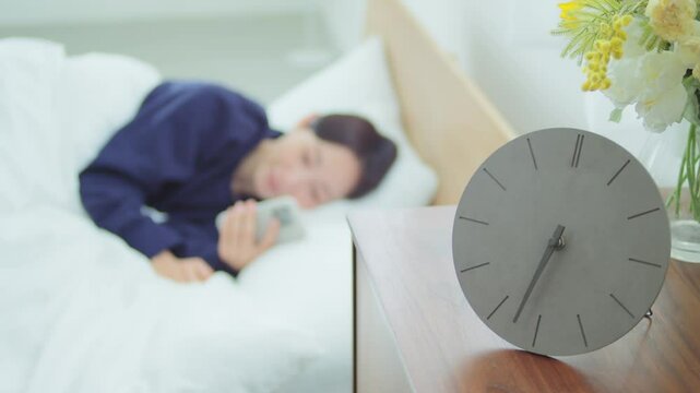 ベッドでスマートフォンを操作する女性