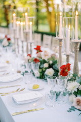 Festive set table with flowers and burning candles in a green park