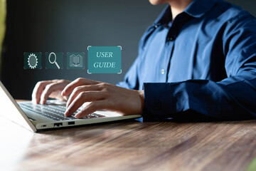 Businessman using laptop with virtual user guide icon for business services, online manuals and strategy guides, showing icons on virtual screen.
