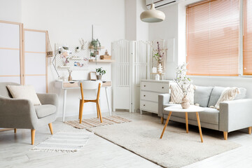 Interior of light office with workplace, pegboard and sofa
