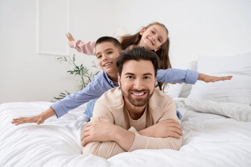 Fototapeta premium Happy father with his little children lying in bedroom