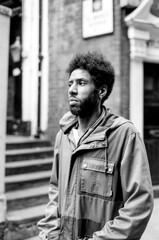 Young man wearing jacket standing in urban setting, grainy monochrome analog photography
