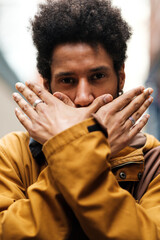 Young man covering his mouth with his hands, freedom of speech concept